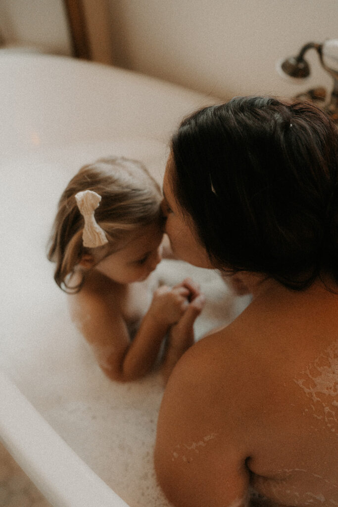 a mother and daughter playing in the bath posing for a mother and daughter photoshoot
